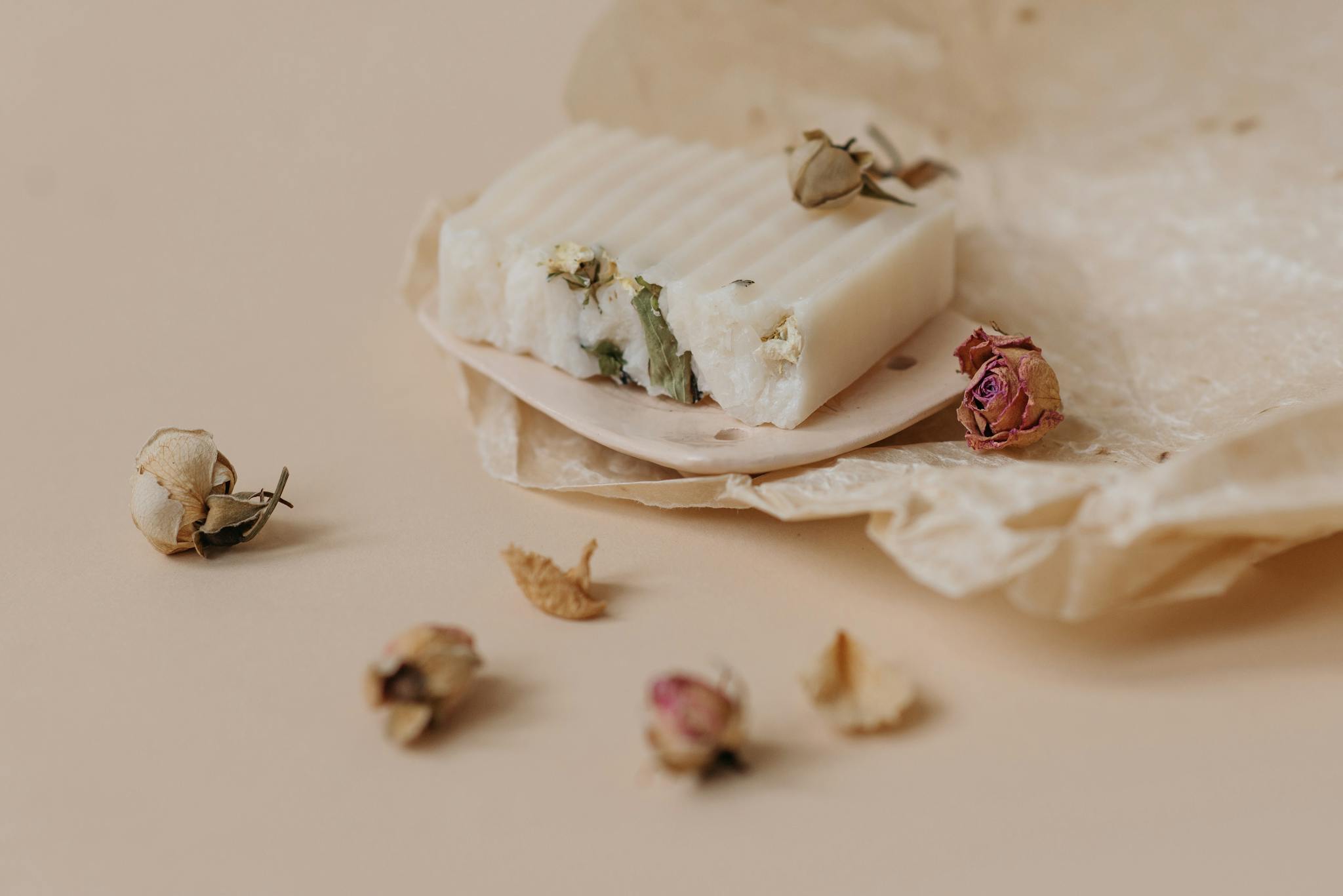 Close-up of artisanal soap with dried flowers on wax paper, eco-friendly product