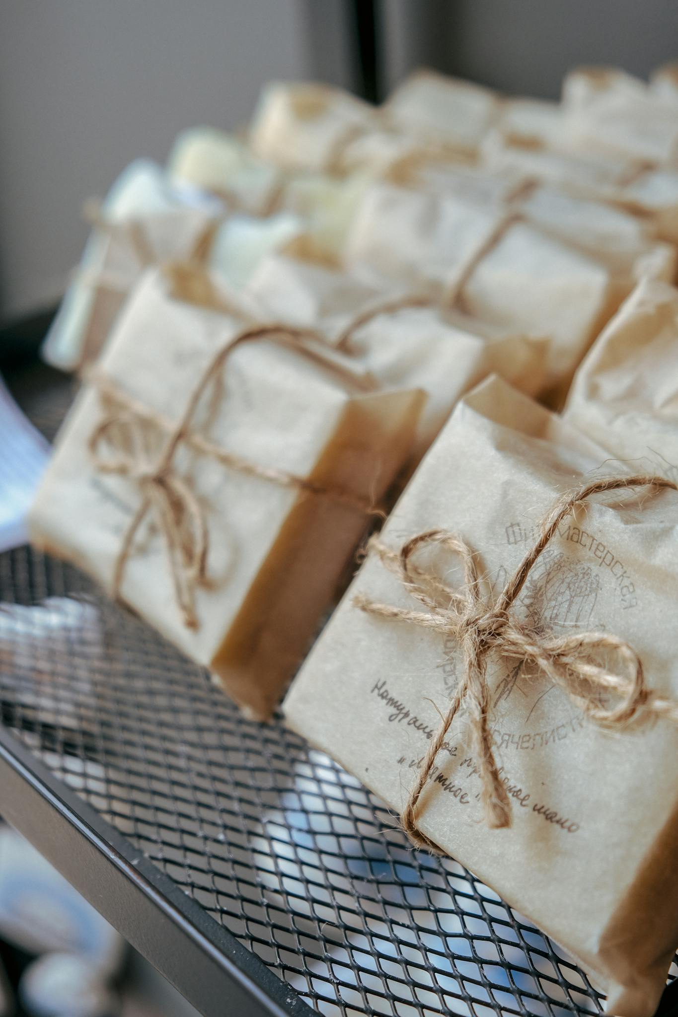 Close-up of handmade soaps wrapped in eco-friendly paper with twine, on a metal rack.